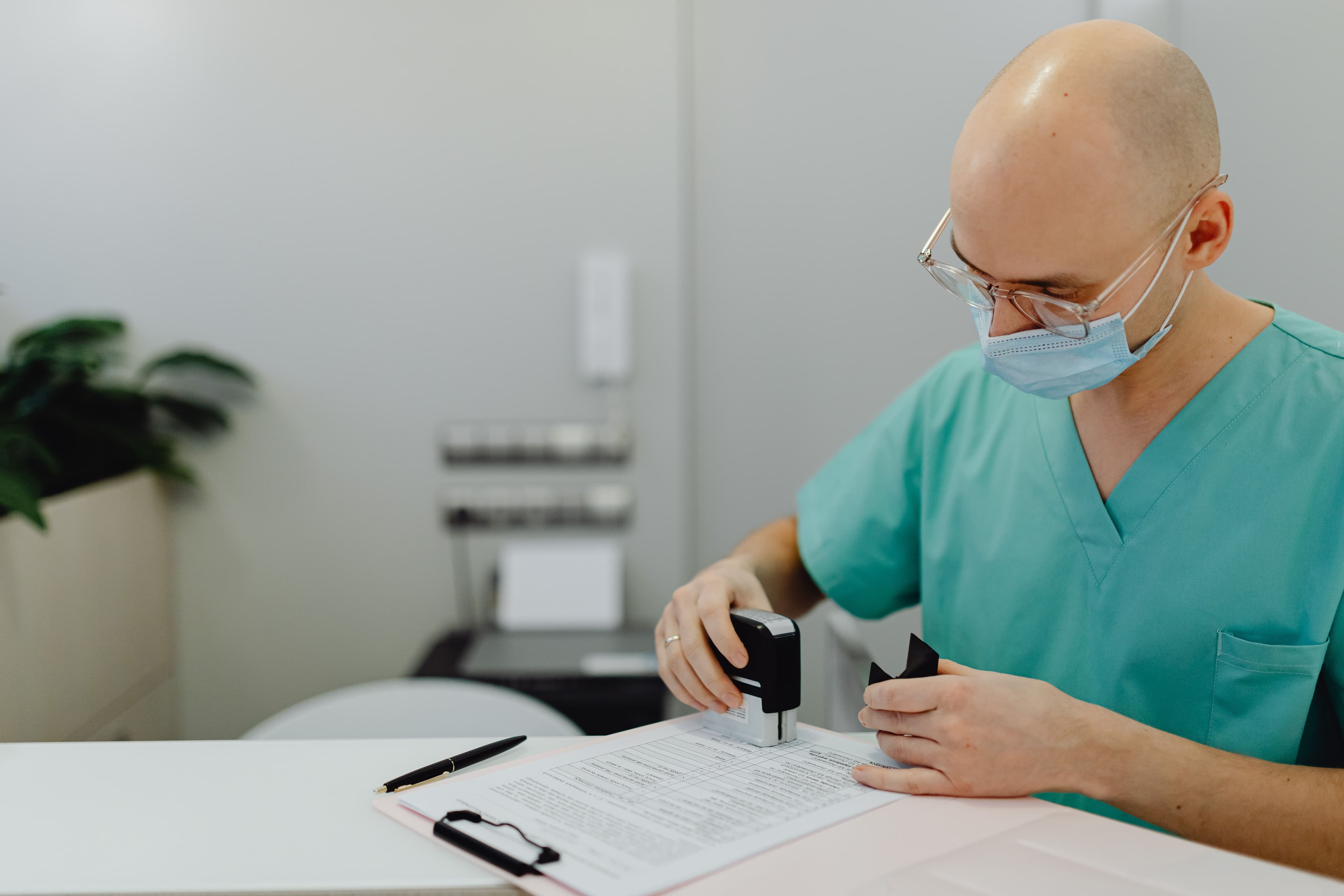 Une professionnelle de santé en tenue médicale relit un dossier administratif posé sur un bureau.