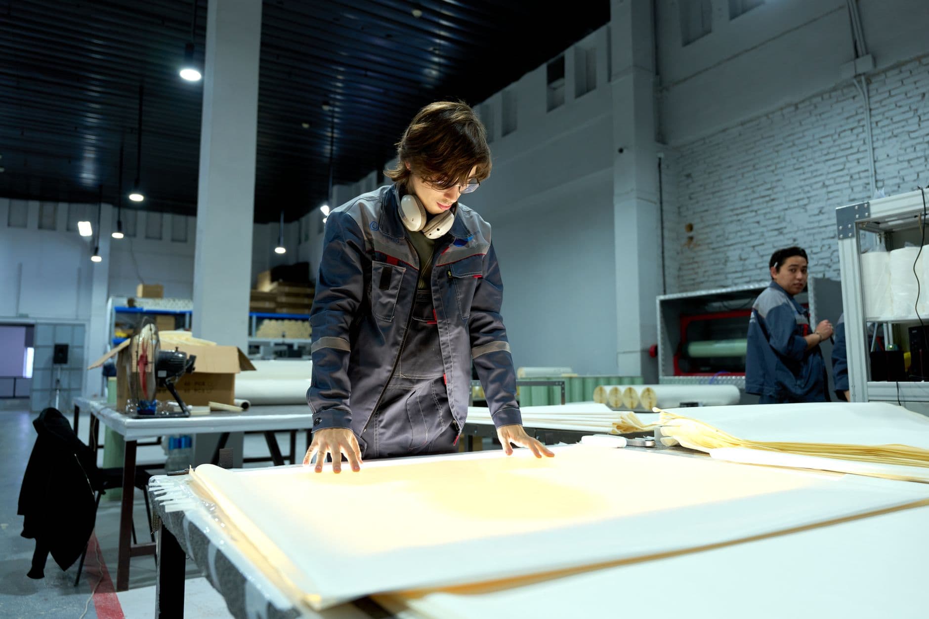Un opérateur inspecte une pièce posée sur une table de contrôle qualité, dans un atelier industriel.